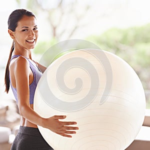 Ready to get on the ball. Portrait of a beautiful young woman holding an exercise ball at home.
