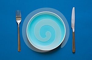 Color plate fork and knife  on blue background.