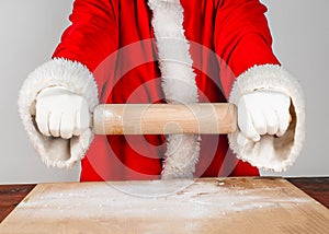 Ready to start cooking. Close-up Santa Claus in traditional costume holds a rolling pin