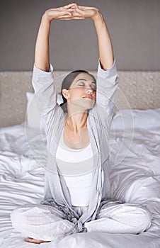 Ready to take on the world. An attractive young woman stretching in bed after waking up.