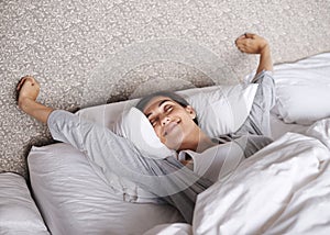 Ready to take on the world. An attractive young woman stretching in bed after waking up.