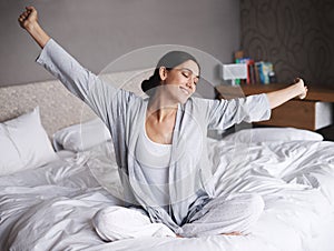 Ready to take on the world. An attractive young woman stretching in bed after waking up.