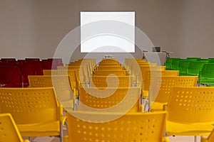 Ready to use rows of colorful chairs in conference room with blank white space on wall as projector screen