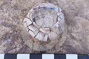 Real archaeological excavations. Aged-damaged clay jar finding in the ground with measure plank.