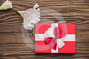 Real box with white and red bow and ribbon top view on Valentine`s day isolated on wooden background. Flat lay. Copy space