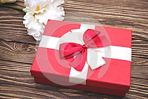 Real box with white and red bow and ribbon top view on Valentine`s day isolated on wooden background. Flat lay. Copy space