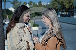 Real couple of young women, holding hands, looking at each other and talking in affectionate attitude. Concept lgtbiq+, lesbians,