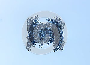 Real culomn snowflake at high magnification. Macro photo of small rimmed snow crystal, snowflake glowing on dark blue