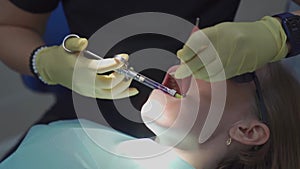 real. dentist injects an anesthetic into patient before tooth extraction