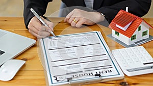 Real estate agent advising clients with contract documents and computers with front view house designs.