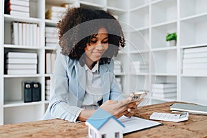 Real estate agent, African American businesswoman Africans use smartphone and calculators to offer mortgages to their