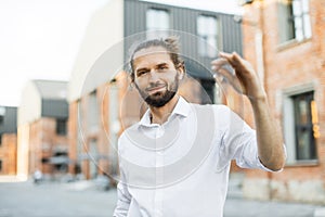 Real estate agent beautiful man with house keys in front of sold apartment, in city street.