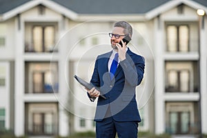 Real estate agent business man in suit hold holder clipboards and talking on phone. Businessman. Business Man broker or