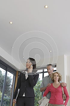 Real Estate Agent On Call With Couple Observing New Property