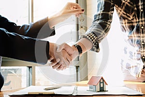 Real estate agent and customers shaking hands together celebrating finished contract after about home insurance and