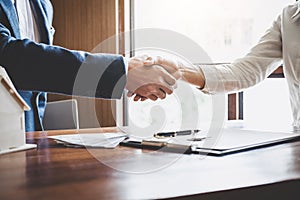 Real estate agent and customers shaking hands together celebrating finished contract after about home insurance and investment