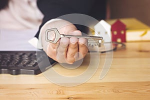 Real estate agent female hand holding a silver key , sell house business concept