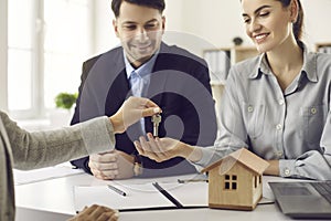 Real estate agent gives key to new house or apartment to happy smiling young couple