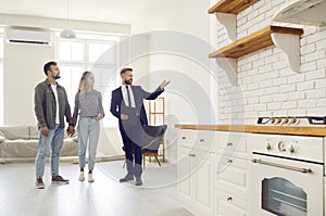 Real estate agent giving his clients tour about all rooms in new house or apartment