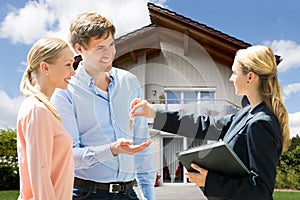 Real Estate Agent Giving House Key To Young Couple