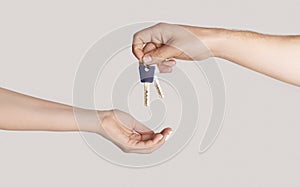 Real estate agent giving house keys to client against light background, close up of hands. Panorama