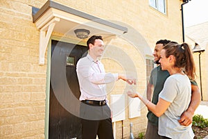 Real estate agent giving house keys to new property owners photo