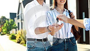 Real estate agent giving house keys to young couple, closeup