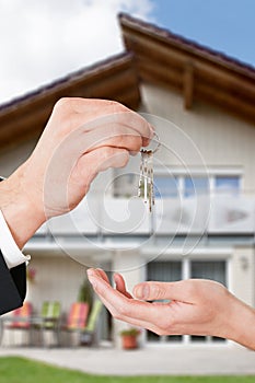 Real Estate Agent Giving Keys To Owner Against New House