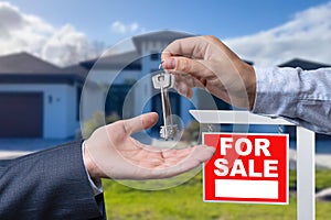 Real Estate Agent Handing Over the House Keys in Front of a Beautiful New Home and For Sale Real Estate Sign.