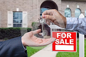 Real Estate Agent Handing Over the House Keys in Front of a Beautiful New Home and For Sale Real Estate Sign.