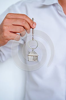 Real estate agent handing over house keys, Men hand holding key with house shaped keychain, Close up focus