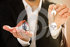 Real Estate agent hoding house model and house key