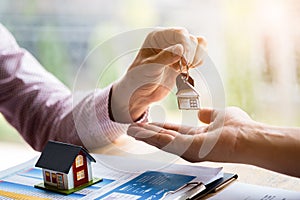 Real estate agent holding filing keys to customer after signing rental lease contract of sale purchase agreement