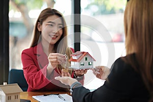 Real estate agent holding house key to his client after signing contract agreement in office,concept for real estate