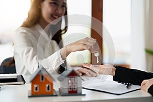 Real estate agent holding house key to his client after signing contract agreement in office,concept for real estate