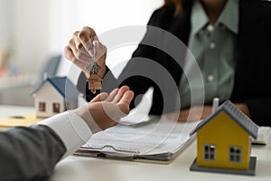 Real estate agent holding house key to his client after signing contract agreement in office,concept for real estate