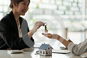 real estate agent holding house key to his client after signing contract agreement in office,concept for real estate
