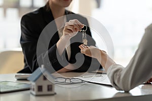 real estate agent holding house key to his client after signing contract agreement in office,concept for real estate