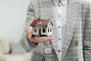 Real estate agent holding house model and key, closeup