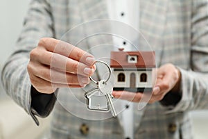 Real estate agent holding house model and key, closeup