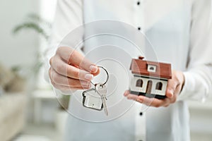 Real estate agent holding house model and key indoors