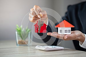 Real estate agent holding house model and keys,  customer signing contract to buy house, insurance or loan real estate