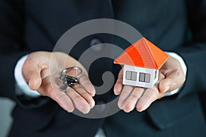 Real estate agent holding house model and keys,  customer signing contract to buy house, insurance or loan real estate