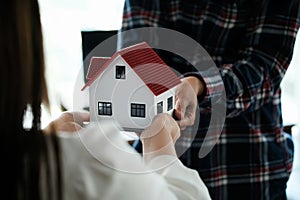 Real estate agent holding house model and pass to customer, Property concept