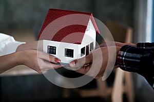 Real estate agent holding house model and pass to customer, Property concept