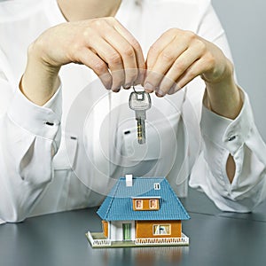 Real estate agent holding key above small house model