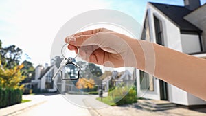 Real estate agent holding key against modern houses, closeup. Banner design