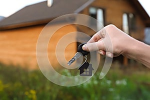 Real estate agent holding key and blurred house on background.