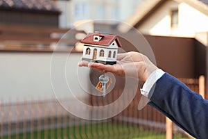 Real estate agent holding key and house model, closeup