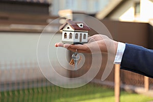 Real estate agent holding key and house model, closeup